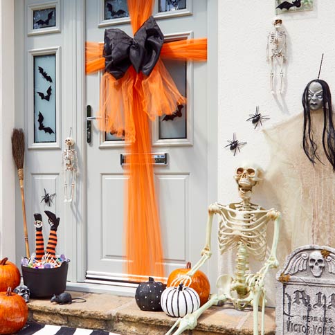 front door decorated for halloween with an organge door bow and skeletons